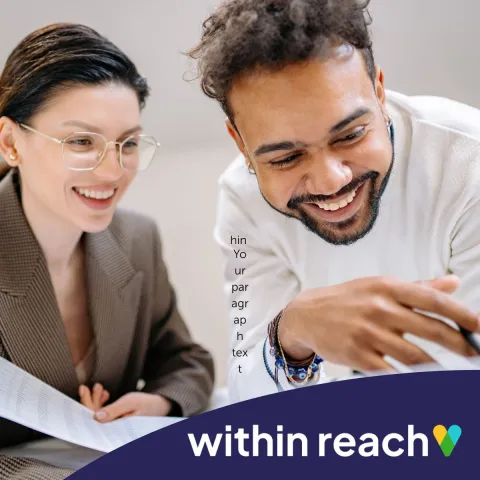 Two people smiling and working together in front of a laptop