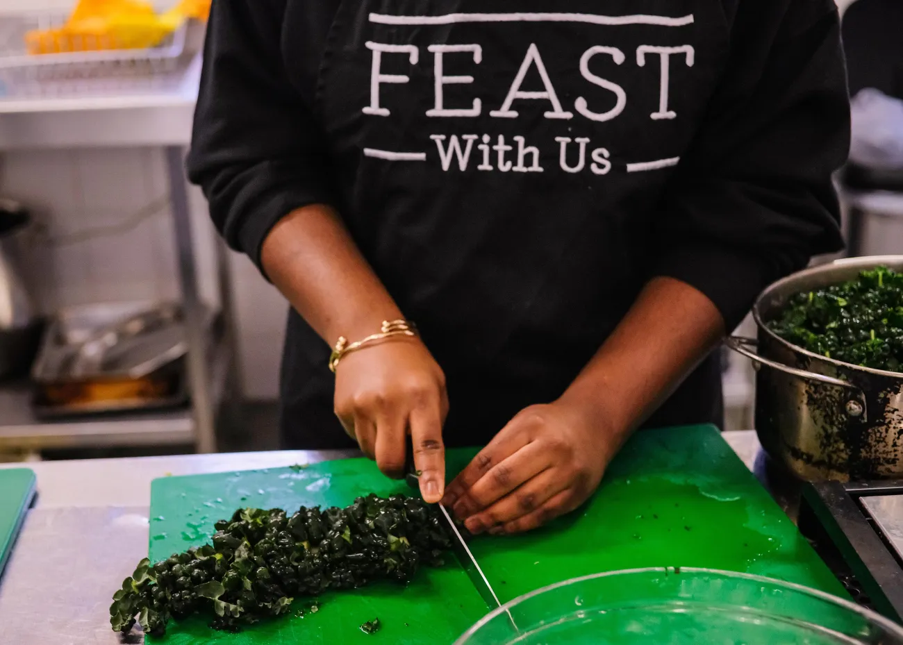 Preparing food wearing a FEAST With Us apron