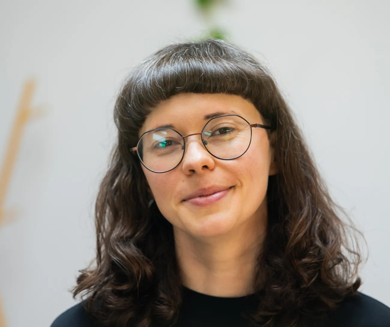 A smiling Simona from Abuelita's Wellbeing in a black top with long black hair and glasses.