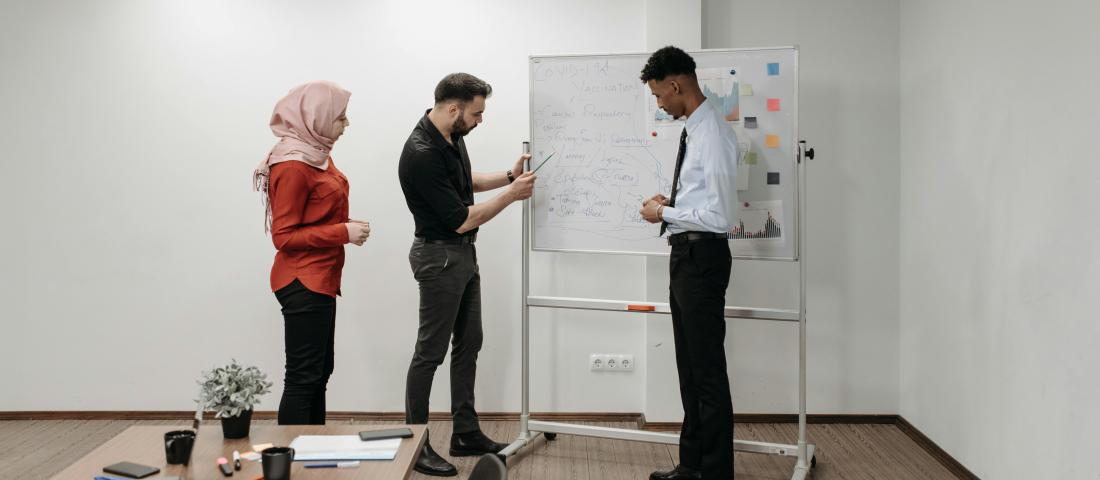 A group of board members standing around a whiteboard