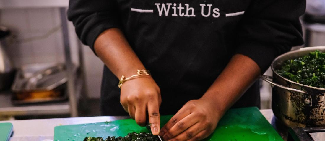 Preparing food wearing a FEAST With Us apron