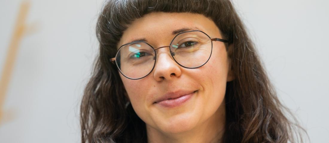 A smiling Simona from Abuelita's Wellbeing in a black top with long black hair and glasses.